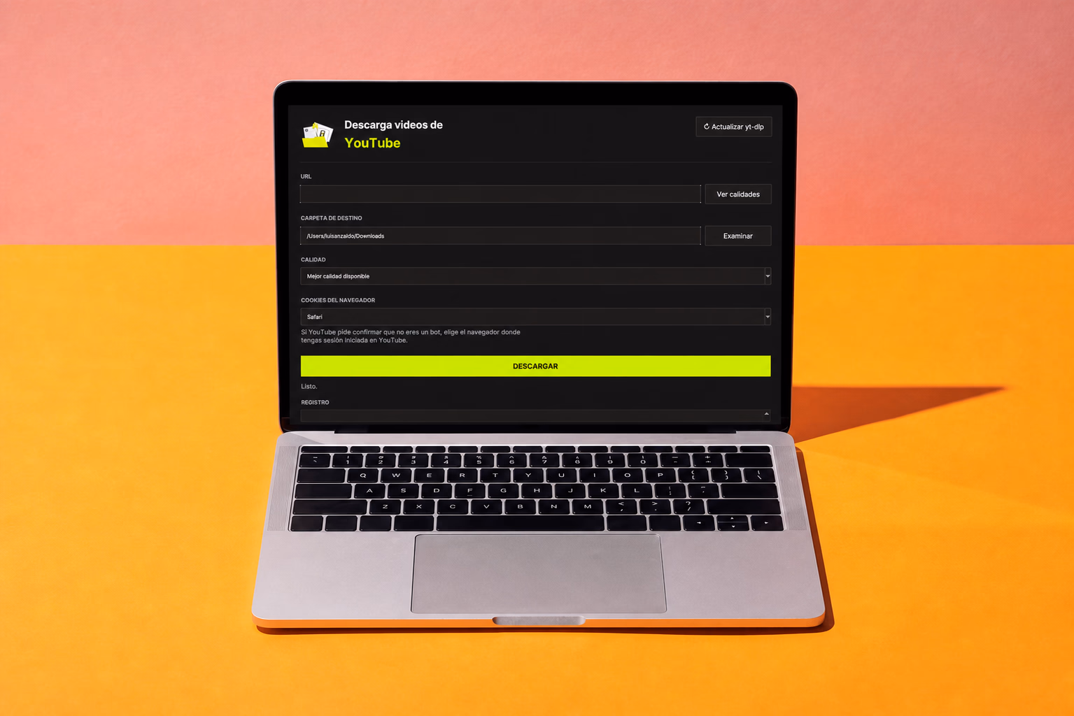 La aplicación abierta en una MacBook sobre un fondo rosa y naranja, con los campos para pegar la URL del video, elegir la carpeta de destino y seleccionar la calidad de descarga